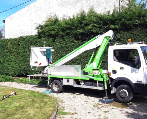 Photo représentant l'activité d'entretien des espaces verts d'OASURE. On observe un camion avec nacelle devant une grande haie à tailler.