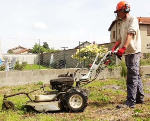 Photo représentant une ancienne activité d'OASURE de service à la personne. Elle est illustré par un salarié en train de passé le motoculteur dans un jardin.