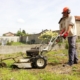 Photo représentant une ancienne activité d'OASURE de service à la personne. Elle est illustré par un salarié en train de passé le motoculteur dans un jardin.