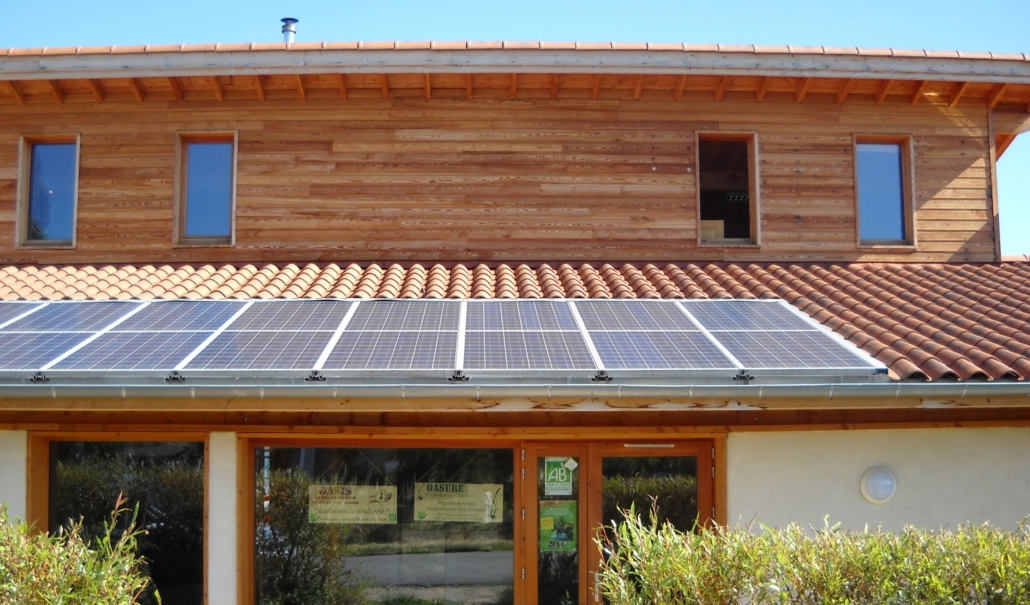 Photo du bâtiment administratif d'OASURE construit en écoconstruction avec de grandes fenêtres et des panneaux solaires sur le toit