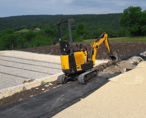 Ouverture d'une tranchée d'ancrage avec une mini pelle pour la mise en place d'une toile pour l'aménagement de talus